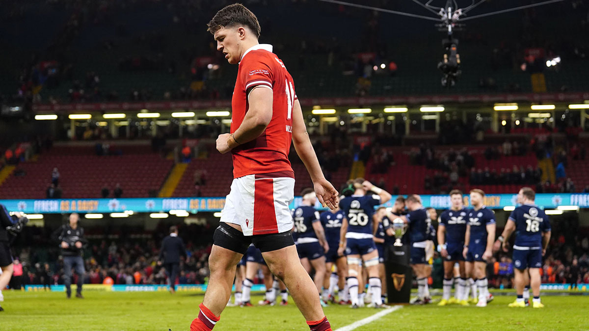 Teddy Williams walks past as Scotland players celebrate with the Doddie Weir Cup